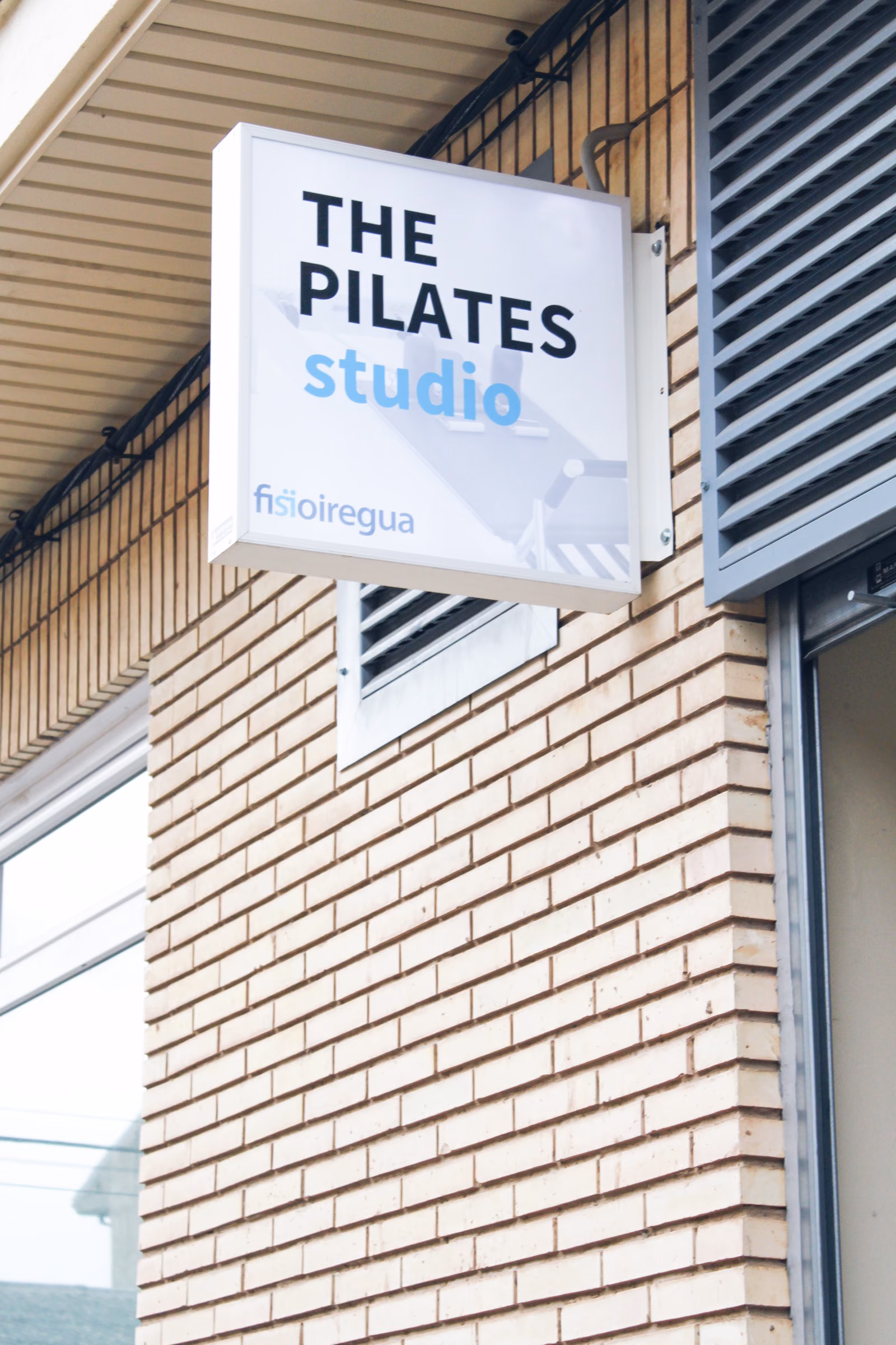 Cartel de The Pilates Studio y Fisioiregua en la fachada